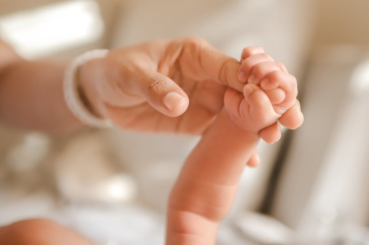 Heartwarming image of a newborn holding an adult's finger, symbolizing connection and care.